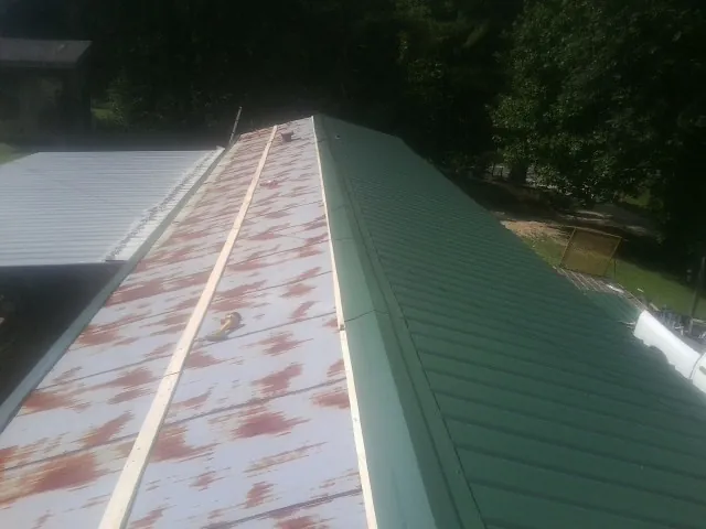 Old rusted panels beside newly installed green metal roofing — Wind Damage Roof Repair by Roofing Brothers in Carr
