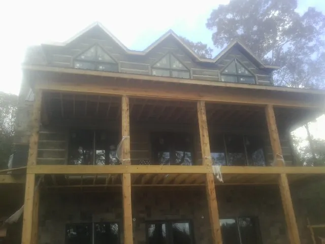 Dormers and porch framing on a large log home under construction — Roof Coating work by our crew in Carr