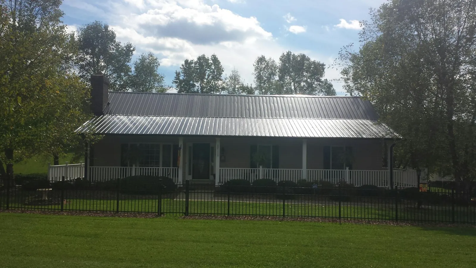 Gray metal roof on a brick ranch with a full width front porch — Gutter Guard Installation work by our crew in Carr