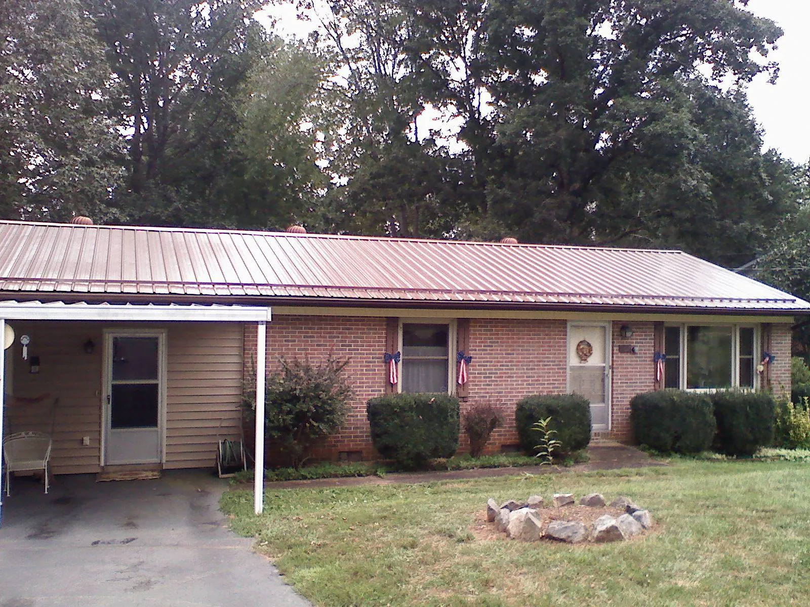 Bronze metal roof and carport on a brick ranch home — Roof Repair work by our crew in Carr