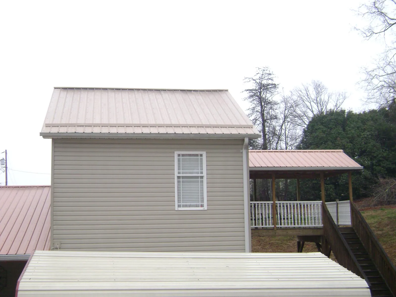 Tan metal roofs on a two story addition and attached porch, from a Roof Replacement job in Carr